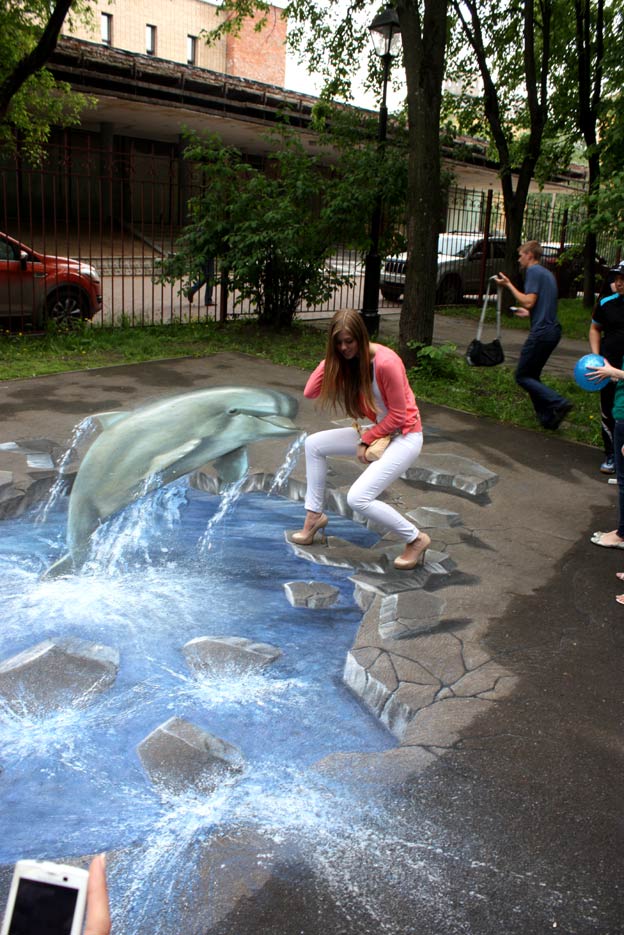 Girl interacting with 3D pavement painting at 3D Pictures on Asphalt Festival, Moscow