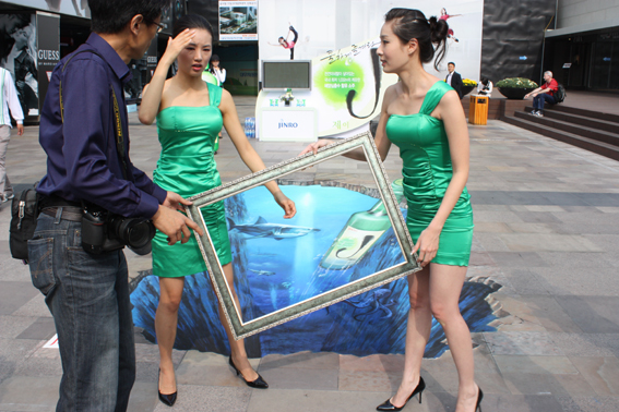 One optical illusion upon another - Jinfro ladies holding a panting frame over 3D art