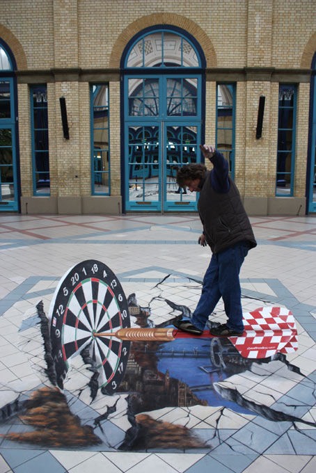 Man interacting with 3D street painting illusion for Ladbrokes, London